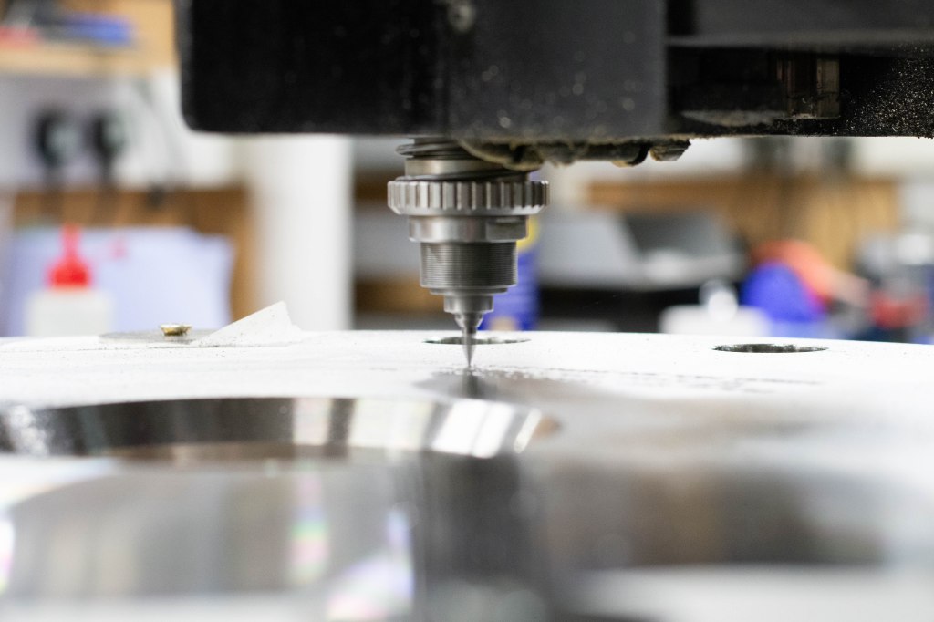 Computerised CNC engraving of a large stainless steel component, viewed from the side.