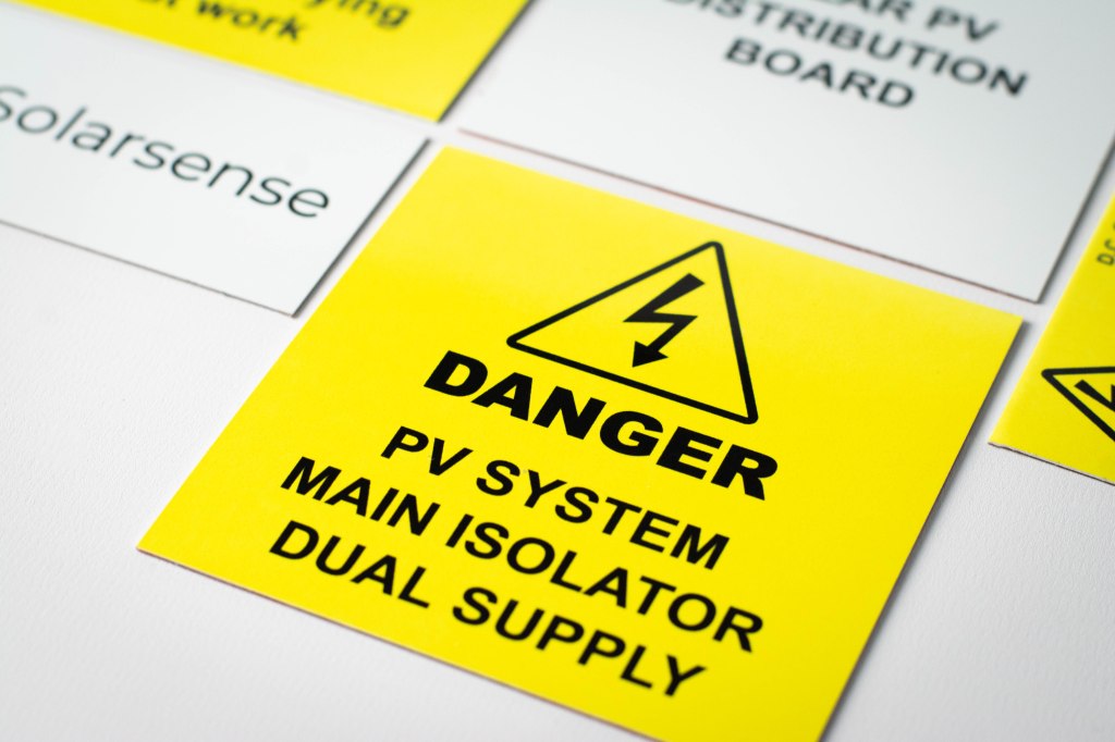 Close up image of printed thin aluminium labels - these are a mix of yellow warning labels and white information labels